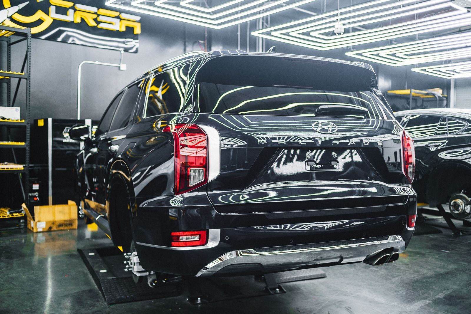 A black SUV on the ramp in a workshop lit by strip lights