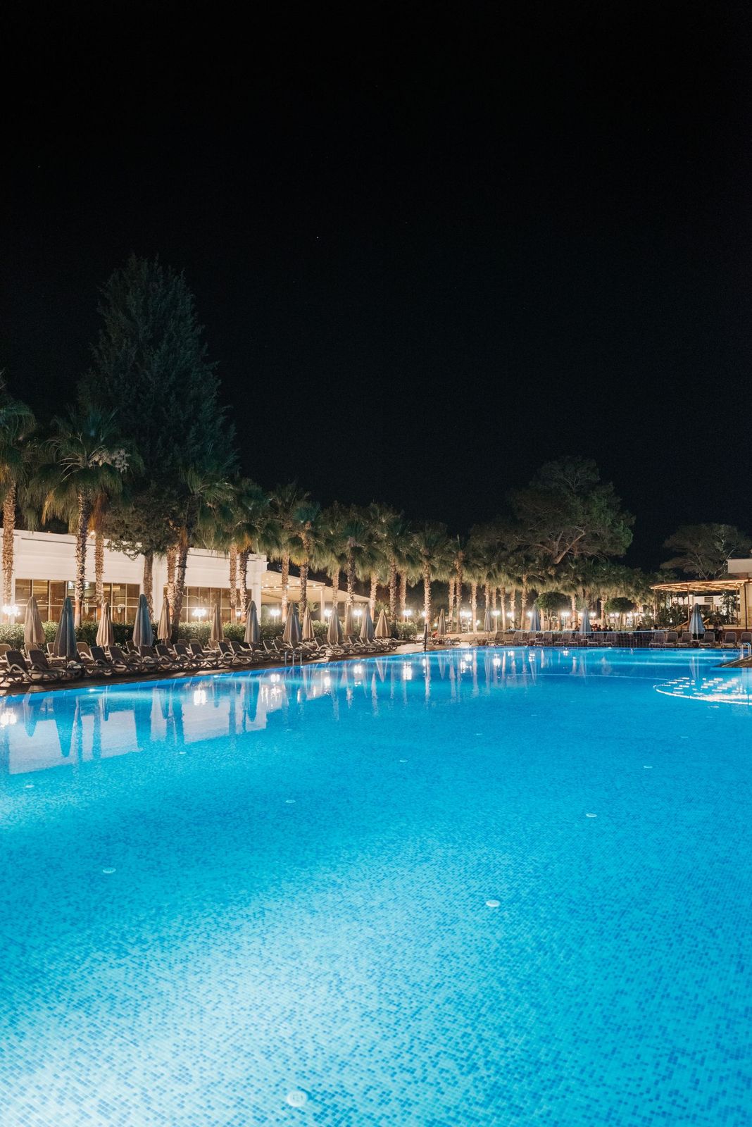 The Meridian's thermal pool lit from below at night, steam rising off the water