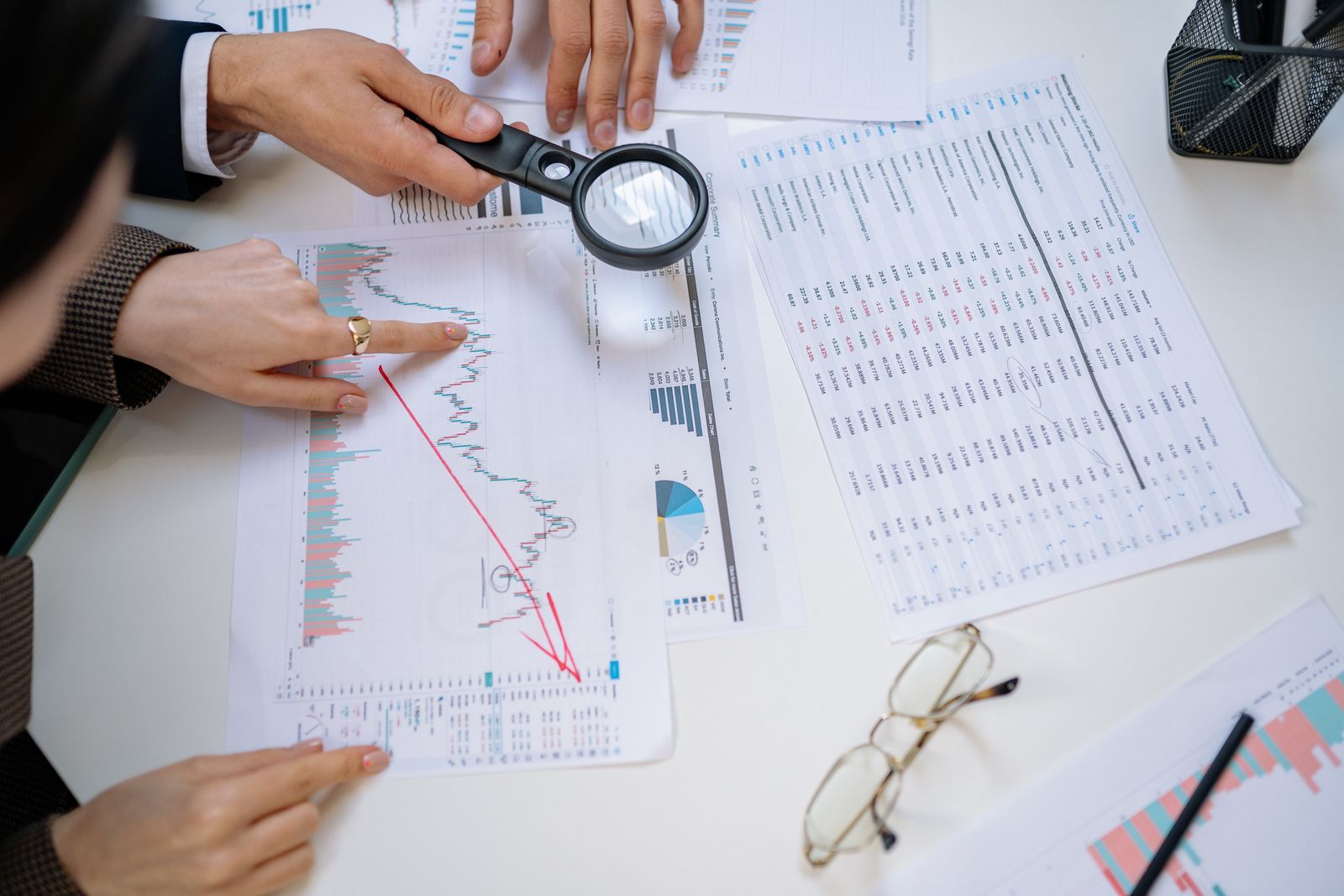 Two people reviewing printed management accounts and charts across a table