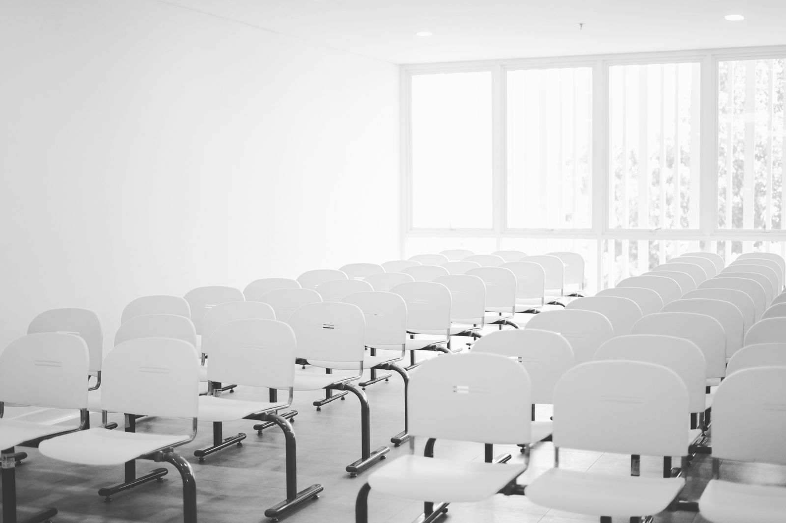 An empty meeting room with white chairs around a long boardroom table