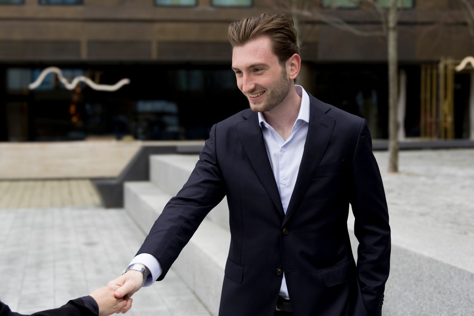Two people shaking hands outside an office building after a meeting