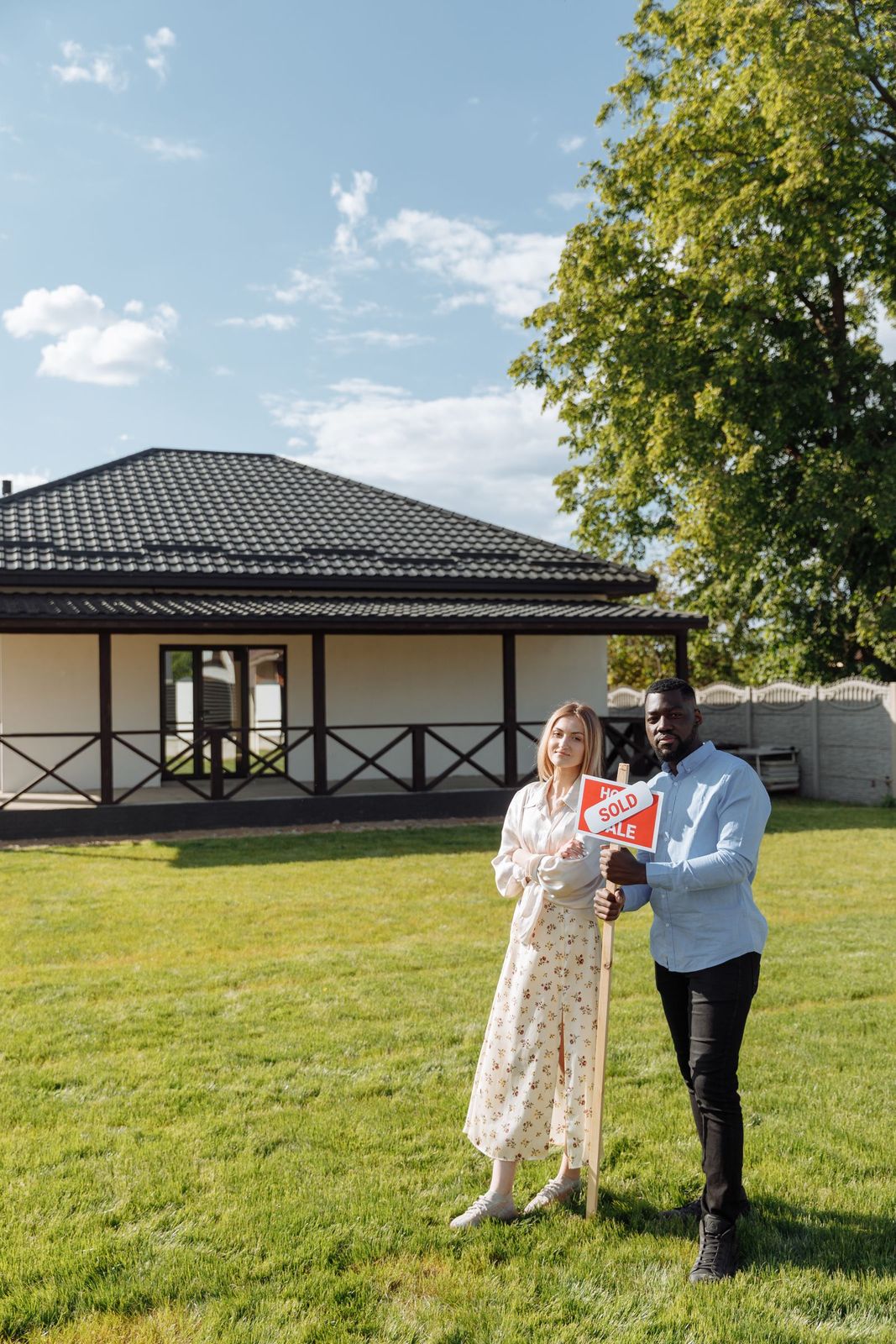 A couple standing in the front garden of a detached house