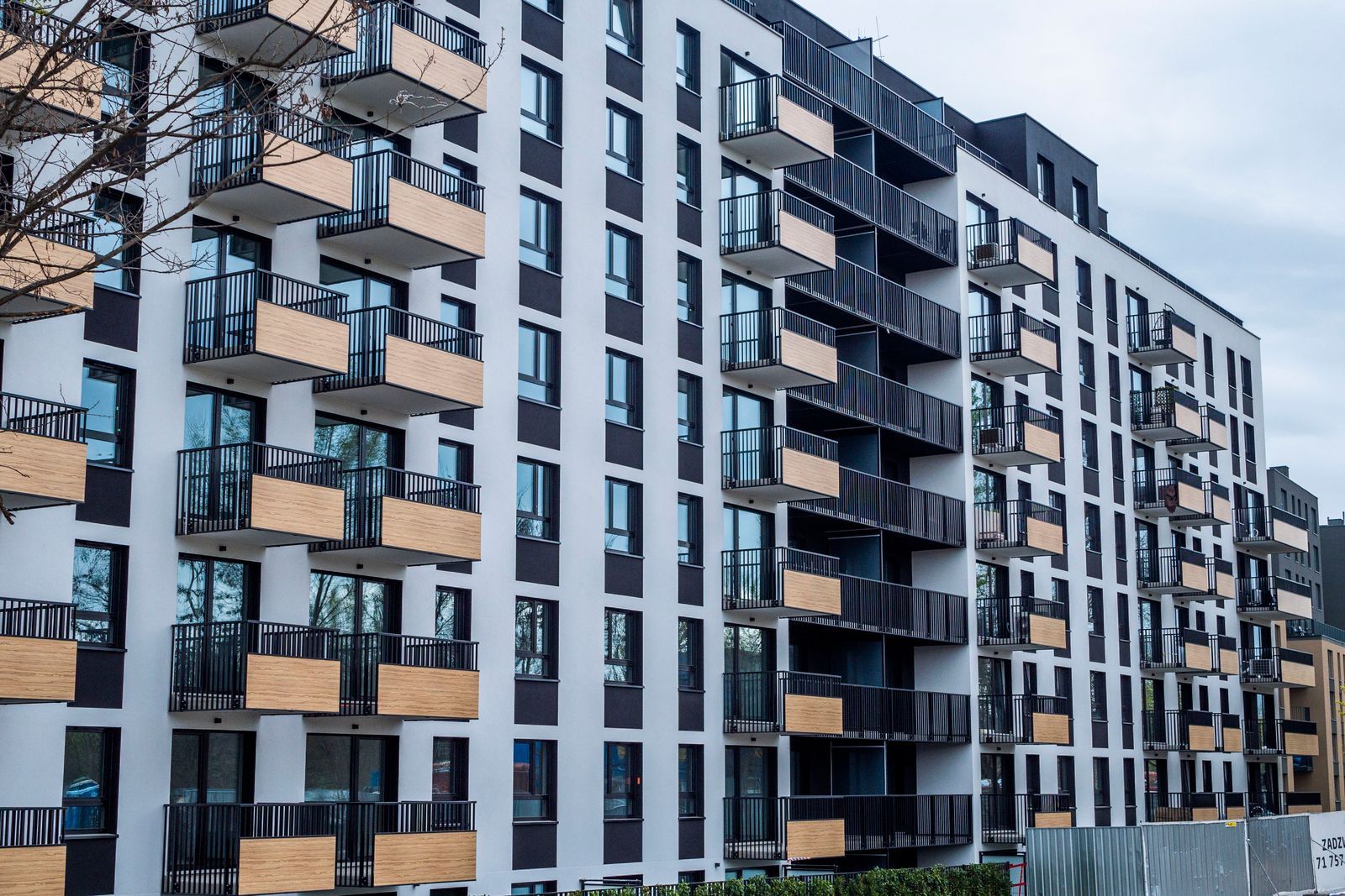 The balconied front elevation of a modern apartment building in grey and white cladding