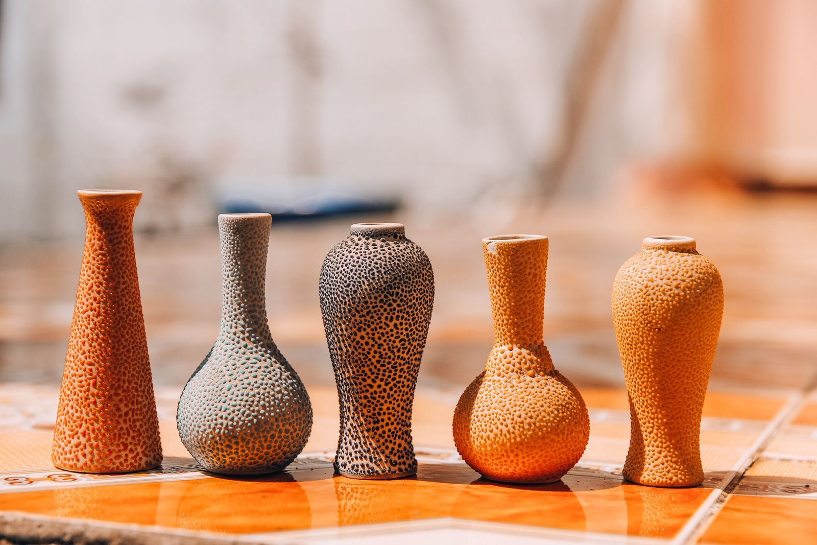 Hand-thrown stoneware vases in sage, clay and cream on a shop shelf