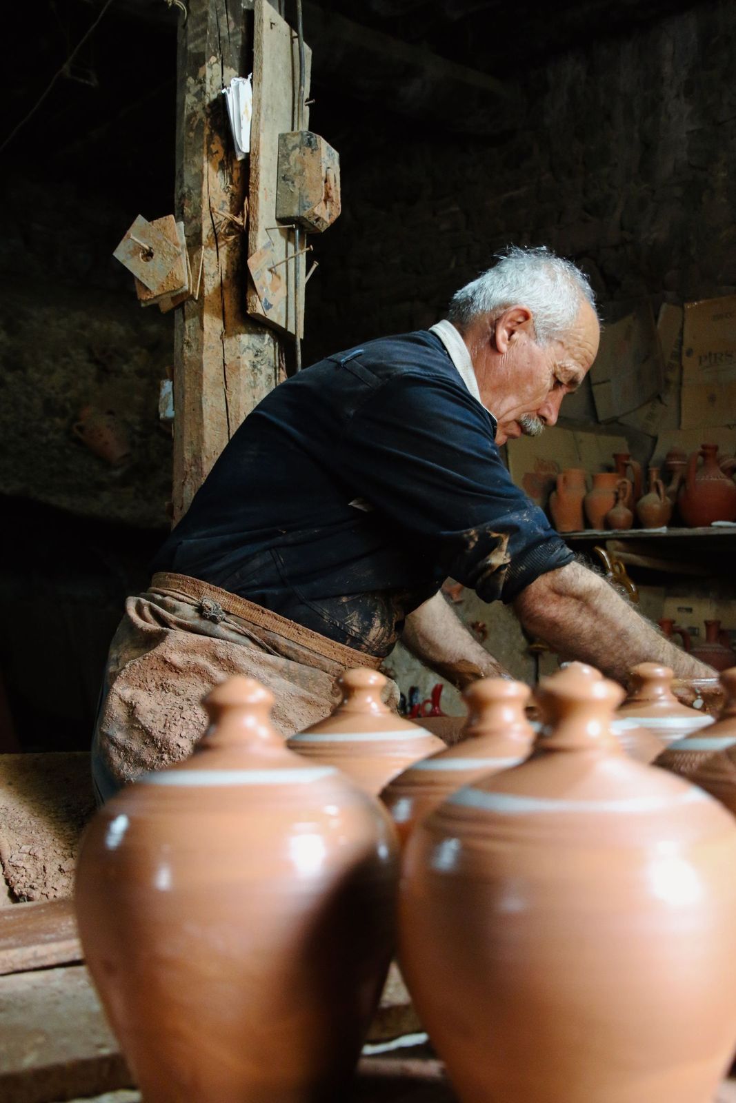 A potter shaping a vase at the wheel in her studio