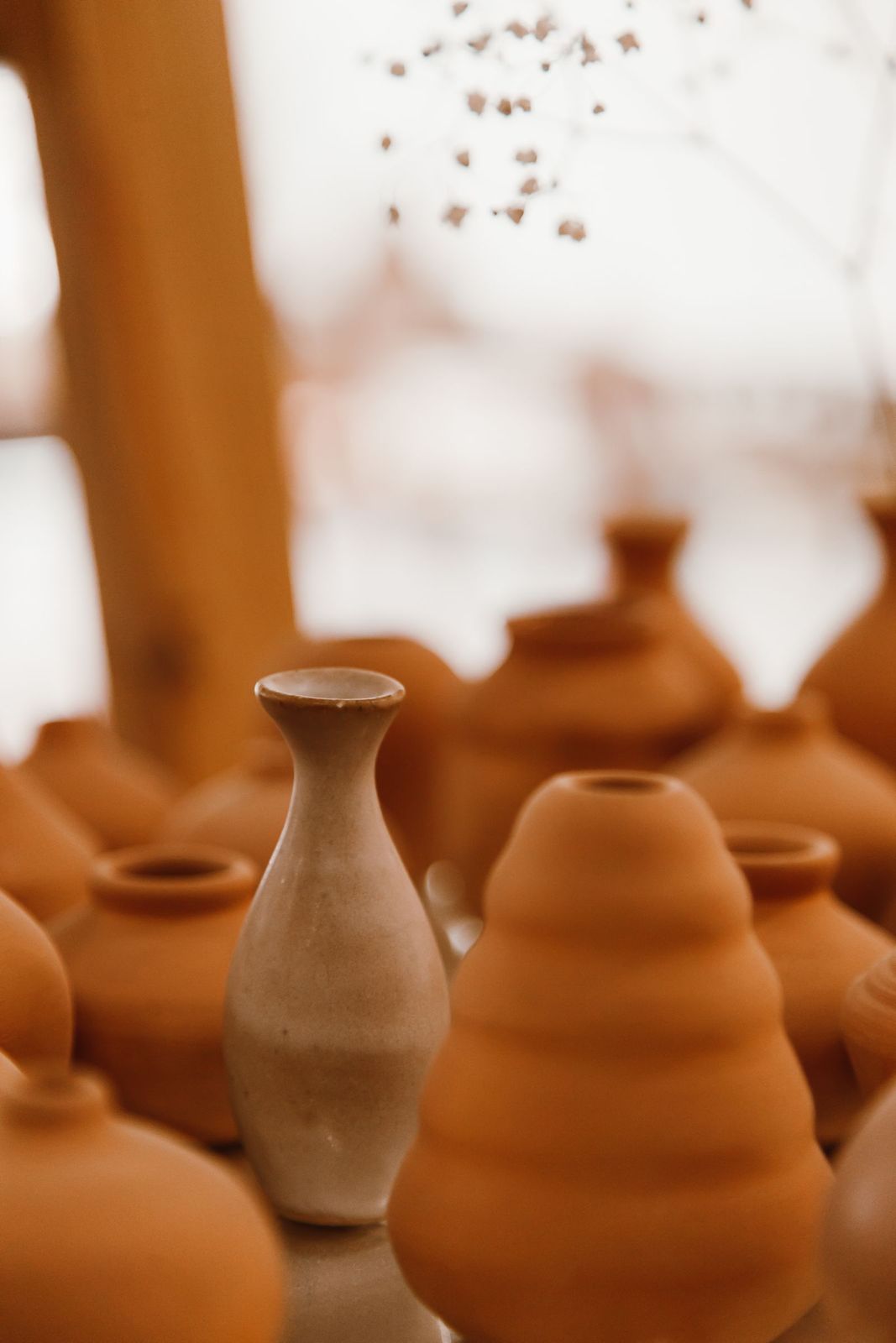 Three small unglazed bud vases grouped together on a shelf